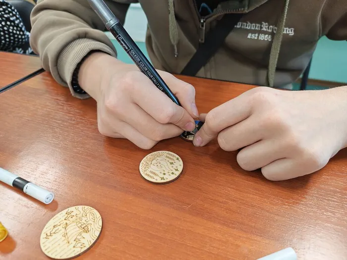 Фото: участник раскрашивает деревянный значок