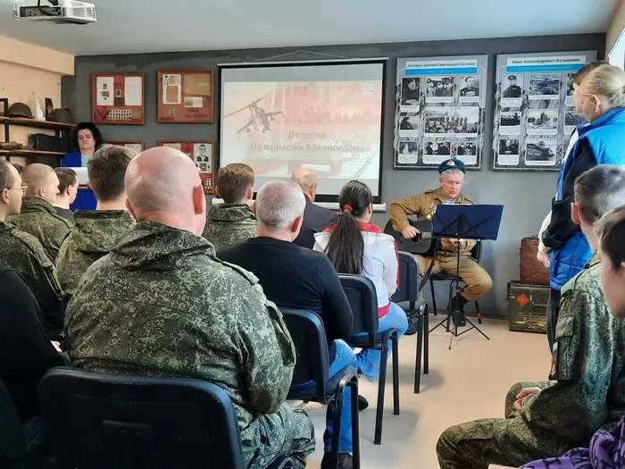 Участники мероприятия слушают выступающего, поющего на гитаре