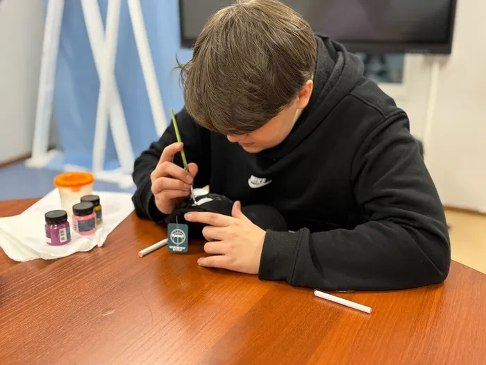 Участник творческой мастерской расписывает кепку