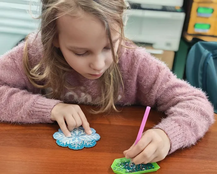 Фото: участница за выполнением алмазной мозаики